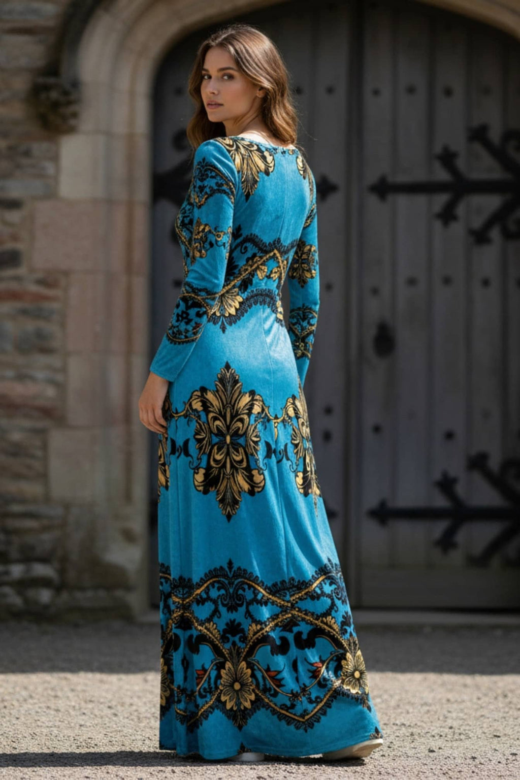 Woman wearing a baroque print velvet maxi dress in blue and gold from Angelic Blessings Shop standing outdoors