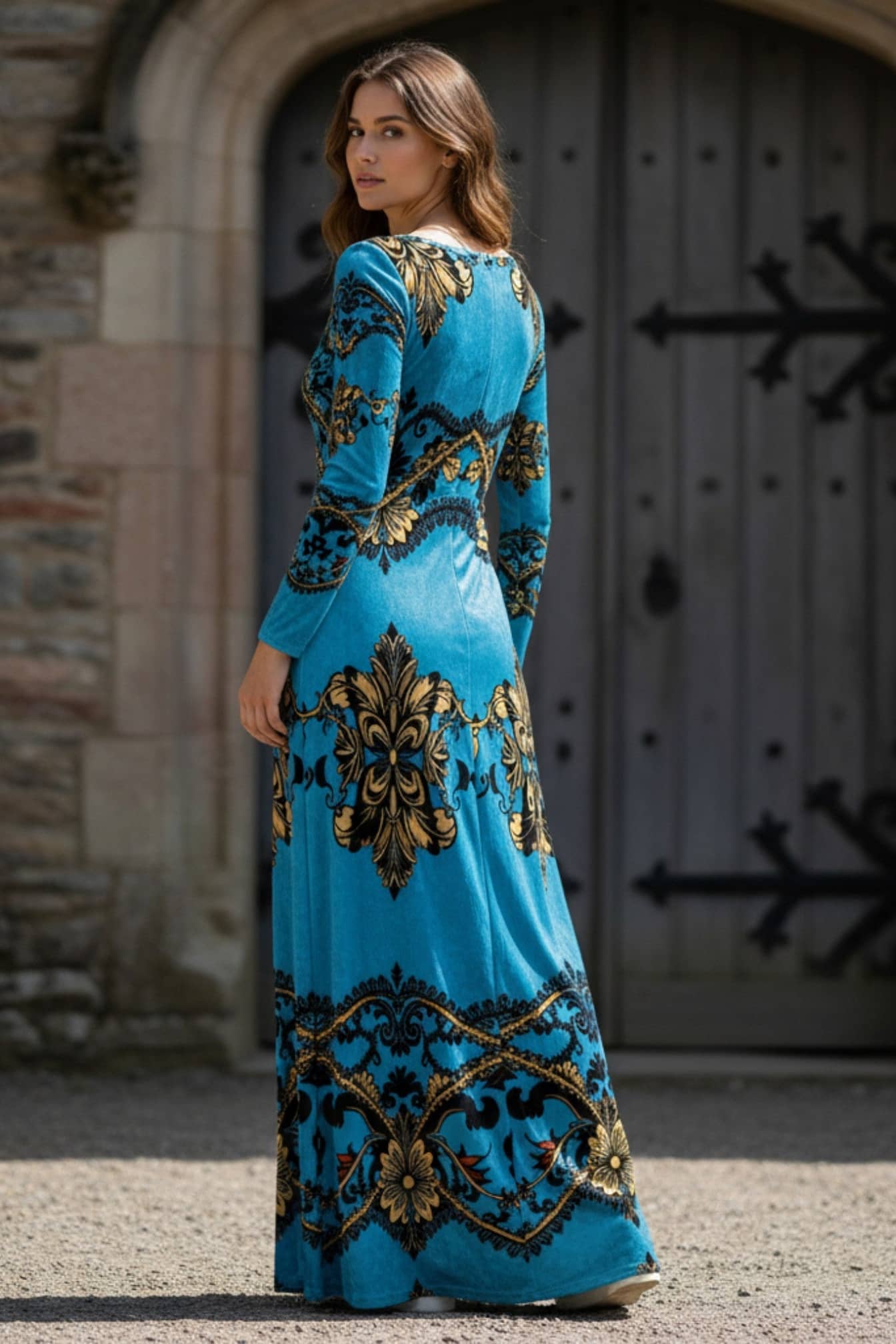 Woman wearing a baroque print velvet maxi dress in blue and gold from Angelic Blessings Shop standing outdoors
