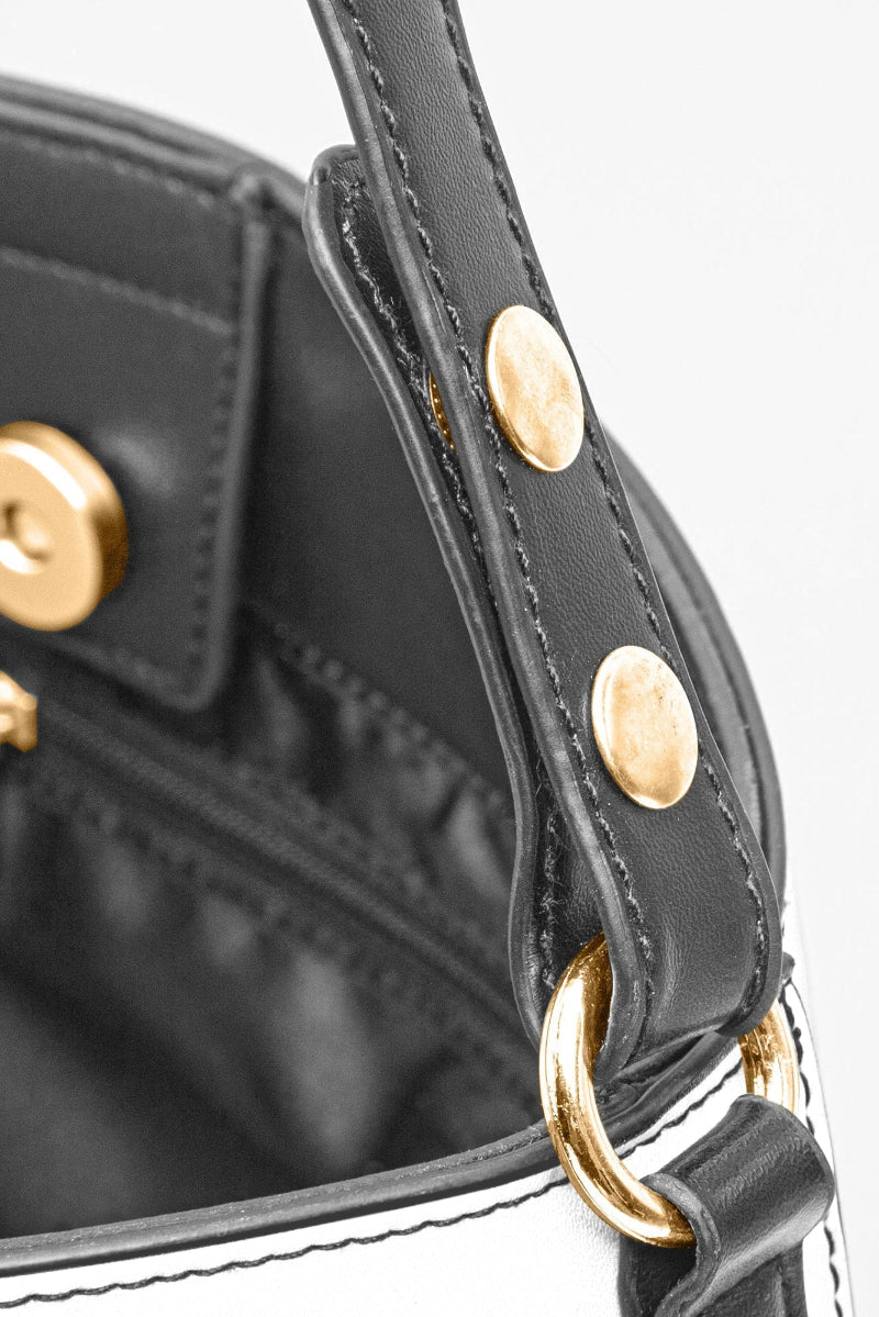 Close-up of black leather strap and gold hardware on a brown baroque print bucket handbag