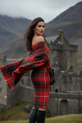 Woman wearing Clan Fraser tartan off shoulder dress with matching shawl near historic stone castle