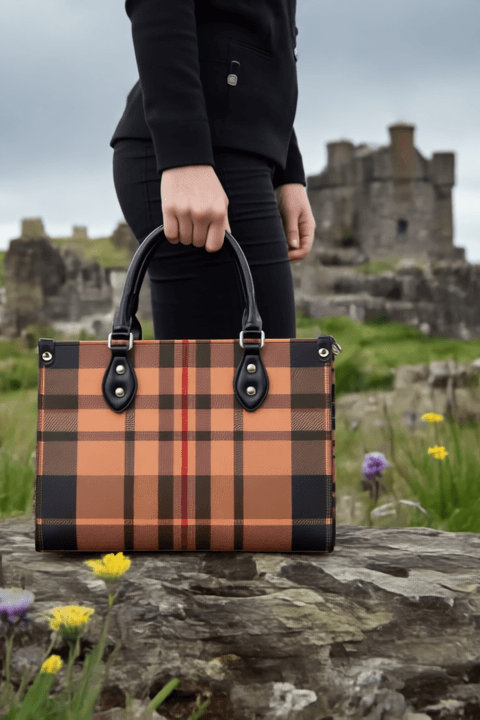 Heritage inspired designer handbags with plaid pattern and black handles held outdoors near ancient ruins